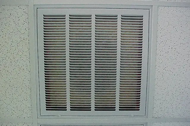 Wide slatted return air grille set into a speckled white ceiling